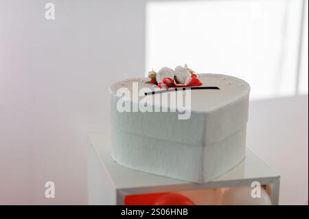 Eleganter Hochzeitstorte in Herzform mit Blumendekoration. Stockfoto