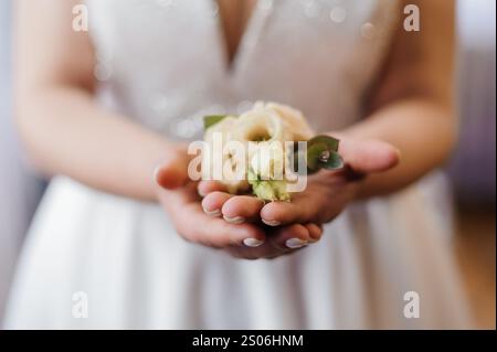 Eine Braut, die eine zarte Hochzeit Boutonnière in den Händen hält. Stockfoto
