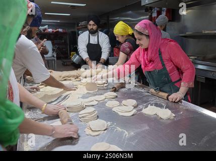 Sikh-Männer und -Frauen verschiedenen Alters machen Roti-Brot in einer langaren, kostenlosen Gemeinschaftsküche im Keller eines Tempels in Richmond Hill, Queens, New York. Stockfoto