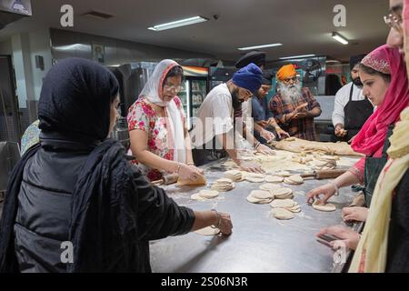 Sikh-Männer und -Frauen verschiedenen Alters machen Roti-Brot in einer langaren, kostenlosen Gemeinschaftsküche im Keller eines Tempels in Richmond Hill, Queens, New York. Stockfoto