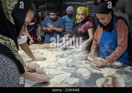 Sikh-Männer und -Frauen verschiedenen Alters machen Roti-Brot in einer langaren, kostenlosen Gemeinschaftsküche im Keller eines Tempels in Richmond Hill, Queens, New York. Stockfoto