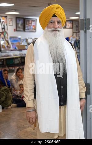 Ein angesehener älterer Sikh-Mann, der einen gelben Dastar Turban und einen langen weißen Schal trägt. In einem Tempel in Queens, New York. Stockfoto