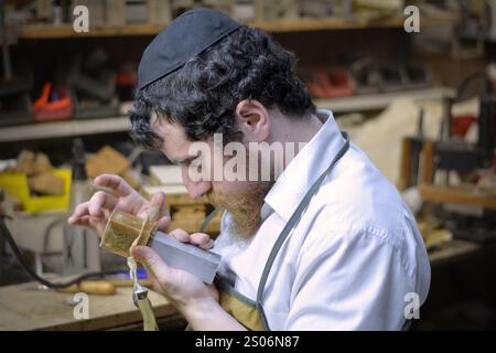 In seiner Werkstatt stellt ein Rabbiner und Handwerker Phylakterien (Tefillin) her, die von orthodoxen Juden während des Morgengebets verwendet werden. In Brooklyn, New York Stockfoto