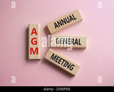 Jahreshauptversammlung – Symbol für Jahreshauptversammlung. Konzeptwort AGM auf Holzblöcken. Schöner rosafarbener Hintergrund. Business- und NGM-Konzept. Kopierbereich. Stockfoto