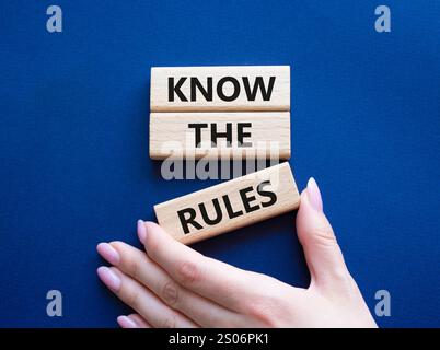Kennen Sie das Regelsymbol. Holzblöcke mit Worten kennen die Regeln. Wunderschöner tiefblauer Hintergrund. Geschäftsmann Hand. Und kennen Sie das Regelkonzept. Stockfoto