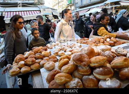 Jerusalem, Israel. Dezember 2024. Die Menschen kaufen Sufganiot, Donuts, auf dem Mahane Yehuda Markt in Jerusalem, in der ersten Nacht des jüdischen Feiertags von Hanukka, dem Lichterfest, am Mittwoch, den 25. Dezember 2024. Hanukkah feiert die Wiedereinweihung des Tempels in Jerusalem im 2. Jahrhundert v. Chr. und das Wunder des Öls. Es ist das erste Mal, dass Hanukka und Weihnachten am selben Tag seit 2005 fallen. Foto: Debbie Hill/ Credit: UPI/Alamy Live News Stockfoto