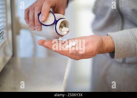 Nahaufnahme der Hände des Mannes, die Tabletten aus der Flasche gießen Stockfoto