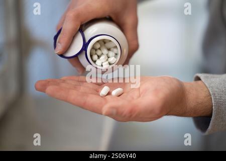 Nahaufnahme der Hände des Mannes, die Tabletten aus der Flasche gießen Stockfoto