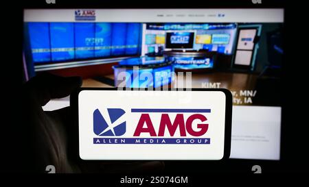 Stuttgart, Deutschland - 07.01.2024: Person mit Mobiltelefon mit Logo des US-Senders Allen Media Group (AMG) vor der Business-Website. Schwerpunkt auf dem Display des Telefons. Stockfoto