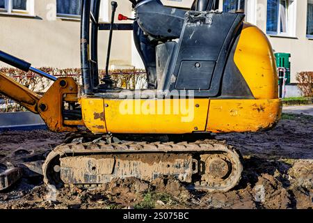 Teil eines kleinen Raupenbaggers, der im Schlamm steht. Fahrerhaus und Ketten. Stockfoto
