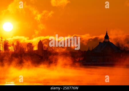 Helsinki, Finnland - 15. Januar 2021: Flammender Morgensonnenaufgang hinter historischem Holzhaus, jetzt Restaurant NJK auf der Insel Valkosaari in Helsinki Archi Stockfoto