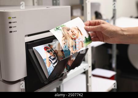 Frau mit bunten Fotos in der Nähe eines modernen Druckers drinnen, Nahaufnahme Stockfoto