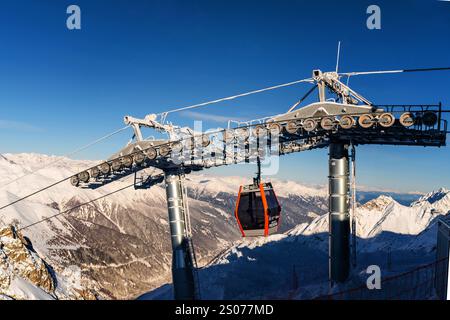 Ponte di Legno, Italien - 03.12.2023: Seilbahn gleitet am hellen Wintertag über schneebedeckte Berggipfel Stockfoto