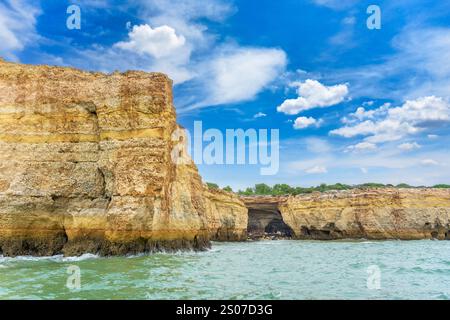 Ein atemberaubender Blick auf die Küste der Algarve mit goldenen Klippen und dramatischen Meereshöhlen. Das türkisfarbene Wasser prallt gegen die zerklüftete Küste, cre Stockfoto