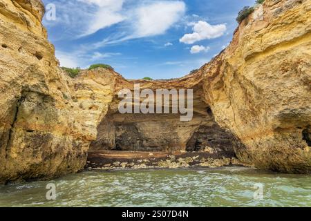 Ein atemberaubender Blick auf die Küste der Algarve mit goldenen Klippen und dramatischen Meereshöhlen. Das türkisfarbene Wasser prallt gegen die zerklüftete Küste, cre Stockfoto