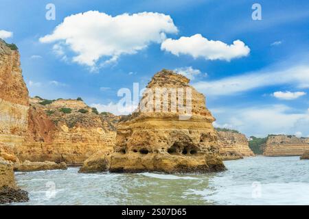 Ein atemberaubender Blick auf die Küste der Algarve mit goldenen Klippen und dramatischen Meereshöhlen. Das türkisfarbene Wasser prallt gegen die zerklüftete Küste, cre Stockfoto