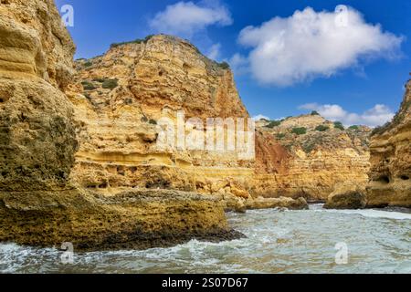 Ein atemberaubender Blick auf die Küste der Algarve mit goldenen Klippen und dramatischen Meereshöhlen. Das türkisfarbene Wasser prallt gegen die zerklüftete Küste, cre Stockfoto