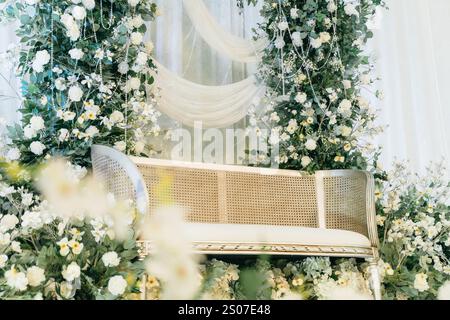 Elegante Blumenhochzeit im Hintergrund mit luxuriösem Sofa, weißen Rosen, Grün und Kristallgirlanden - perfekt für Hochzeiten und besondere Veranstaltungen Stockfoto