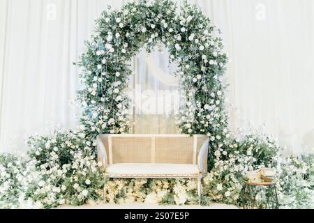 Elegante Blumenhochzeit im Hintergrund mit weißem und grünem Design, luxuriöse Blumenarrangements und ein minimalistischer Beistelltisch für eine romantische Veranstaltung Stockfoto