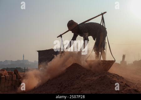 Dhaka, Dhaka, Bangladesch. Dezember 2024. Ein Arbeiter, der in einer Ziegelei in Dhaka, Bangladesch, arbeitet. Jeden Tag wird die Luft durch den schwarzen Rauch verschmutzt, der von den Ziegelfeldern ausgeht. Als Ergebnis der Arbeit auf Ziegelfeldern in einer verschmutzten Umgebung ohne jegliche Schutzausrüstung leiden Ziegelarbeiter an vielen komplexen Krankheiten, einschließlich Atemwegserkrankungen. (Kreditbild: © Abu Sufian Jewel/ZUMA Press Wire) NUR REDAKTIONELLE VERWENDUNG! Nicht für kommerzielle ZWECKE! Quelle: ZUMA Press, Inc./Alamy Live News Stockfoto