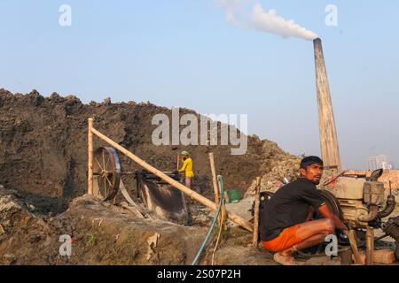 Dhaka, Dhaka, Bangladesch. Dezember 2024. Am 26. Dezember 2024 arbeiten Arbeiter in einer Ziegelei in Dhaka, Bangladesch. Täglich wird die Luft durch den schwarzen Rauch verschmutzt, der von den Ziegelfeldern ausgeht. Als Ergebnis der Arbeit auf Ziegelfeldern in einer verschmutzten Umgebung ohne jegliche Schutzausrüstung leiden Ziegelarbeiter an vielen komplexen Krankheiten, einschließlich Atemwegserkrankungen. (Kreditbild: © Abu Sufian Jewel/ZUMA Press Wire) NUR REDAKTIONELLE VERWENDUNG! Nicht für kommerzielle ZWECKE! Quelle: ZUMA Press, Inc./Alamy Live News Stockfoto