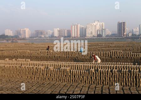 Dhaka, Dhaka, Bangladesch. Dezember 2024. Am 26. Dezember 2024 arbeiten Arbeiter in einer Ziegelei in Dhaka, Bangladesch. Täglich wird die Luft durch den schwarzen Rauch verschmutzt, der von den Ziegelfeldern ausgeht. Als Ergebnis der Arbeit auf Ziegelfeldern in einer verschmutzten Umgebung ohne jegliche Schutzausrüstung leiden Ziegelarbeiter an vielen komplexen Krankheiten, einschließlich Atemwegserkrankungen. (Kreditbild: © Abu Sufian Jewel/ZUMA Press Wire) NUR REDAKTIONELLE VERWENDUNG! Nicht für kommerzielle ZWECKE! Quelle: ZUMA Press, Inc./Alamy Live News Stockfoto