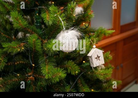 Ein Weihnachtsbaum mit einem weißen Ornament. Das Ornament ist sternförmig und von grünen Blättern umgeben Stockfoto