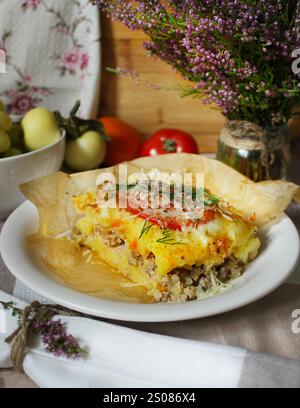 Köstlicher Kartoffelauflauf mit Hackfleisch, Käse und Kräutern, die in Pergamentpapier gebacken werden Stockfoto