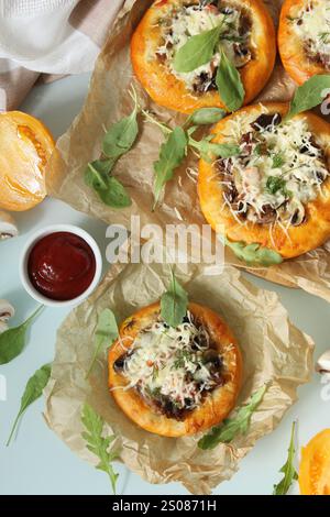 Köstliche Mini-Pizzen mit Pilzen, Käse und Rucola, serviert mit einer Schüssel Tomatensauce Stockfoto