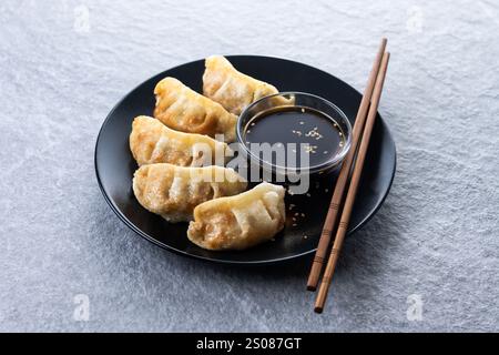 Gebratene Knödel Gyoza mit Sojasauce auf grauem Steingrund Stockfoto