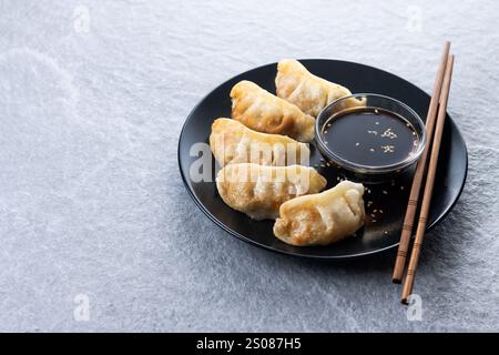 Gebratene Knödel Gyoza mit Sojasauce auf grauem Steingrund Stockfoto