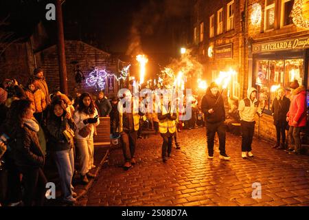 Haworth, West Yorkshire, Vereinigtes Königreich: Im Dezember findet jedes Jahr eine Fackelprozession statt. Flsming-Fackeln werden auf der steilen Main Street in Haworth Whi getragen Stockfoto