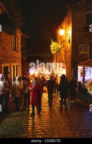 Haworth, West Yorkshire, Vereinigtes Königreich: Im Dezember findet jedes Jahr eine Fackelprozession statt. Flsming-Fackeln werden auf der steilen Main Street in Haworth Whi getragen Stockfoto