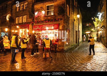 Haworth, West Yorkshire, Vereinigtes Königreich: Im Dezember findet jedes Jahr eine Fackelprozession statt. Flsming-Fackeln werden auf der steilen Main Street in Haworth Whi getragen Stockfoto