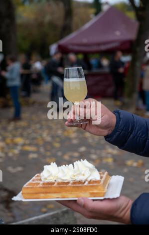 Weinfest in Schengen, Luxemburg, französischen oder luxemburgischen Waffeln mit Schlagsahne und einem Glas Jungwein, der im Herbst im Freien gegessen wird Stockfoto