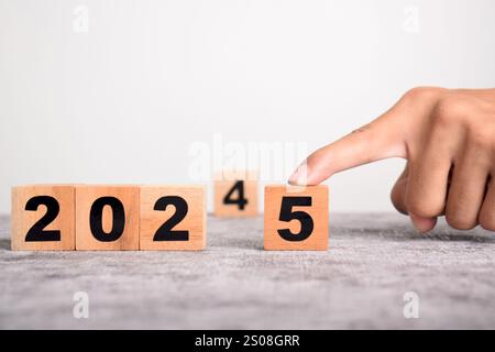 Eine Hand ersetzt 2024 durch 2025 mit Holzwürfelblöcken. Geschäftsplanung und Countdown bis 2025 Stockfoto