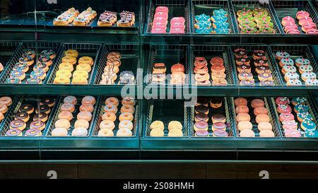 Vitrine gefüllt mit bunten Donuts in verschiedenen Formen und Dekorationen Stockfoto