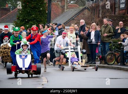 East Hoathly, Großbritannien. Dezember 2024. Kinderwagenrennen am Boxing Day: Teams in schicken Kleidern laufen durch das Dorf East Hoathly in East Sussex und sammeln Spenden für lokale Wohltätigkeitsorganisationen. Die jährliche Veranstaltung beginnt und endet im Kings Head Pub im Zentrum des Dorfes. Quelle: Jim Holden/Alamy Live News Stockfoto
