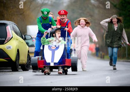 East Hoathly, Großbritannien. Dezember 2024. Kinderwagenrennen am Boxing Day: Teams in schicken Kleidern laufen durch das Dorf East Hoathly in East Sussex und sammeln Spenden für lokale Wohltätigkeitsorganisationen. Die jährliche Veranstaltung beginnt und endet im Kings Head Pub im Zentrum des Dorfes. Quelle: Jim Holden/Alamy Live News Stockfoto