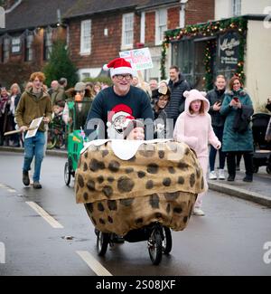 East Hoathly, Großbritannien. Dezember 2024. Kinderwagenrennen am Boxing Day: Teams in schicken Kleidern laufen durch das Dorf East Hoathly in East Sussex und sammeln Spenden für lokale Wohltätigkeitsorganisationen. Die jährliche Veranstaltung beginnt und endet im Kings Head Pub im Zentrum des Dorfes. Quelle: Jim Holden/Alamy Live News Stockfoto