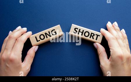 Symbol kurz vs lang. Konzeptwort kurz vs lang auf Holzblöcken. Geschäftsmann Hand. Wunderschöner tiefblauer Hintergrund. Geschäftlich und kurz vs. Lang Stockfoto