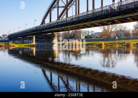 Gorzow Wielkopolski, Polen - 01. Dezember 2024: Eisenbahnbrücke über den Fluss Warta und seine Reflexion im Wasser. Stockfoto