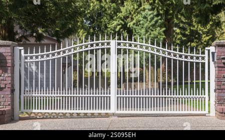 Weißes Metall-Zauntor eines luxuriösen Hauses. Frontklappe aus robustem Metall. Schmiedeeisernes schwarzes Tor. Niemand, Straßenfoto, selektiver Fokus. Außentore. N Stockfoto