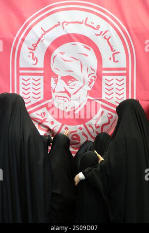 Teheran, Iran. Dezember 2024. Iranische verschleierte Schulmädchen laufen unter einem Porträt von Generalmajor Qasem Soleimani, der bei einem US-Drohnenangriff in Bagdad am 3. Januar 2020 während seiner Jubiläumsfeier im Azadi Indoor Stadium im Westen Teherans getötet wurde. (Kreditbild: © Rouzbeh Fouladi/ZUMA Press Wire) NUR REDAKTIONELLE VERWENDUNG! Nicht für kommerzielle ZWECKE! Stockfoto