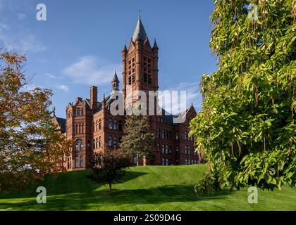 Das Crouse College auf dem Campus der Syracuse University steht majestätisch auf einem üppig grünen Rasen, umgeben von lebendigen Bäumen unter einem klaren blauen Himmel. Stockfoto