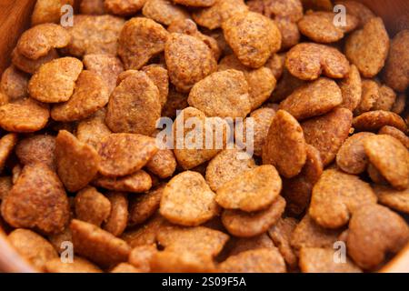 Knusprige Leckereien in Herzform mit brauner, knuspriger Textur in rustikaler Holzschale. Tierfutter. Nahaufnahme. Draufsicht Stockfoto