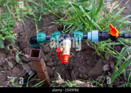 Installation der Tropfbewässerung. Verteilereinheit der Bewässerungsanlage im Garten im Frühjahr. Stockfoto