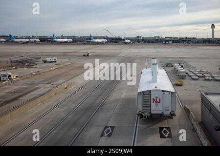 Eine geschäftige Szene am Flughafen Dulles, Washington, mit Bussen, die zwischen Terminals verkehren, eingerahmt vom Kontrollturm und geerdeten Flugzeugen. Stockfoto