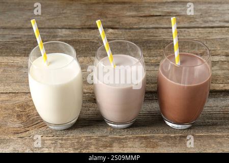 Verschiedene leckere Proteincocktails in Gläsern auf Holztisch Stockfoto
