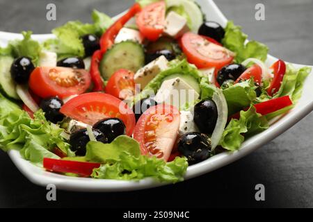 Köstlicher frischer griechischer Salat auf schwarzem Tisch, Nahaufnahme Stockfoto